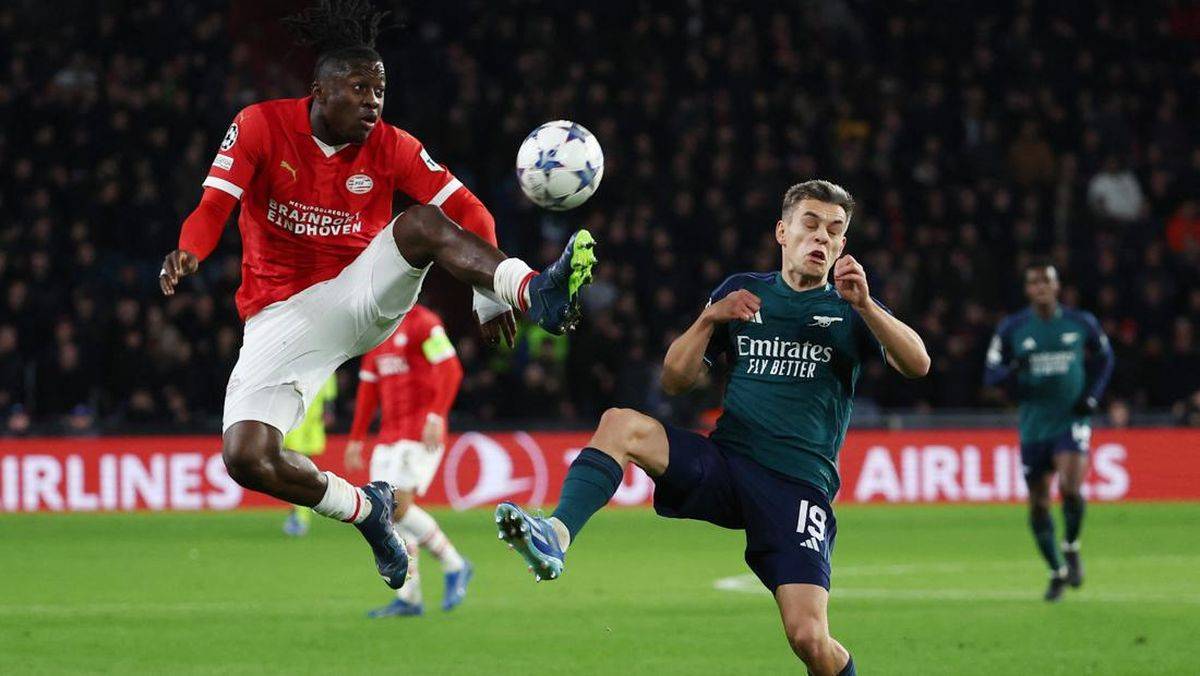PSV Eindhoven facing Arsenal in a UEFA Champions League 2025 match, with players in action on the pitch, showcasing competitive European football.